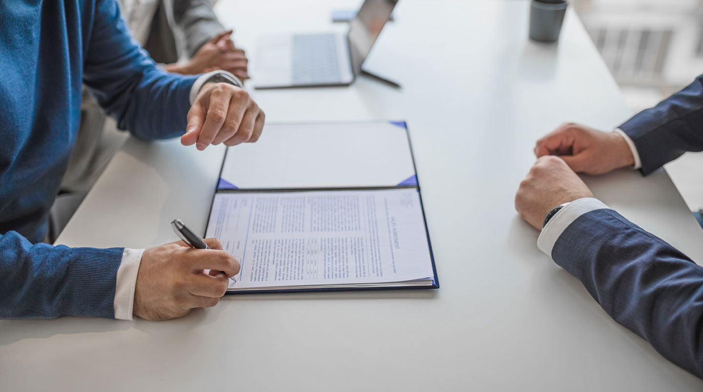 Gros plan sur un contrat de travail français avec passages surlignés en jaune concernant les clauses d'exclusivité et de non-concurrence, mains tenant un stylo
